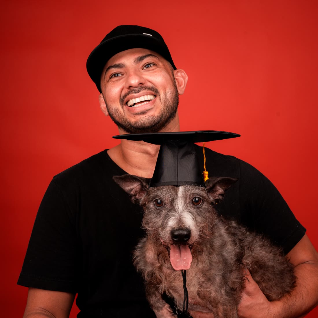 Nestor Ortiz holding a happy pup in a graduation cap